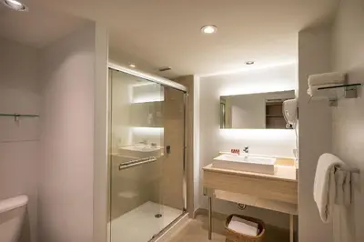 a bathroom with a glass shower and a sink at Hotel Chateau Bromont in Bromont