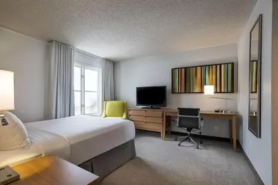 a hotel room with a bed and a desk and a television at Hotel Chateau Bromont in Bromont