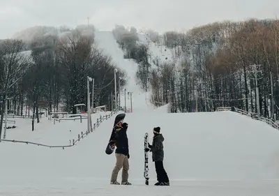 two people standing in the snow with their snowboards at Hotel Chateau Bromont in Bromont