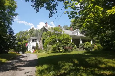 a white house with a driveway in the grass at L'Alcôve des Céramistes in Waterloo