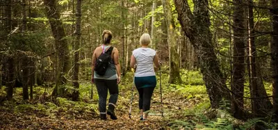 two women walking on a trail in the woods at À la croisée des sommets in Notre-Dame-Des-Bois