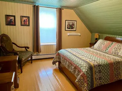 a bedroom with a bed and a chair and a window at À la croisée des sommets in Notre-Dame-Des-Bois