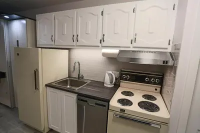 a kitchen with white cabinets and a stove and a refrigerator at Magog Waterfront Studio 106 in Magog-Orford