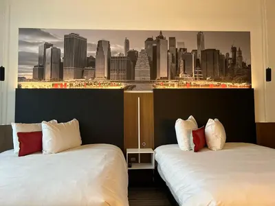 two beds in a hotel room with a view of a city at Grand Hotel TiMES Blainville-Mirabel in Blainville