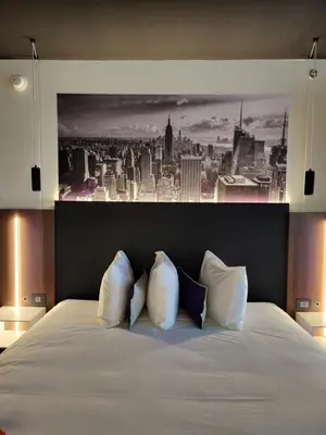 a bedroom with a white bed with a painting on the wall at Grand Hotel TiMES Blainville-Mirabel in Blainville