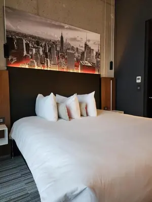 a bedroom with a white bed with a painting on the wall at Grand Hotel TiMES Blainville-Mirabel in Blainville