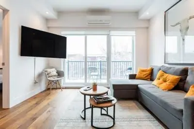 a living room with a couch and a flat screen tv at Hip, Stylish Apartment In Little Italy by Den Stays in Montréal