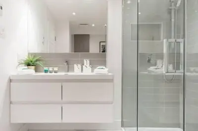 a bathroom with a glass shower and a sink at Hip, Stylish Apartment In Little Italy by Den Stays in Montréal