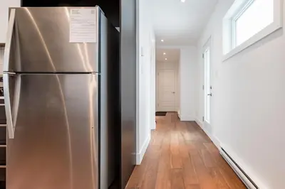 a stainless steel refrigerator in a kitchen with a hallway at Hip, Stylish Apartment In Little Italy by Den Stays in Montréal