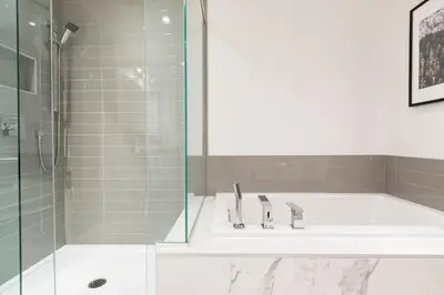 a bathroom with a tub and a shower and a sink at Hip, Stylish Apartment In Little Italy by Den Stays in Montréal