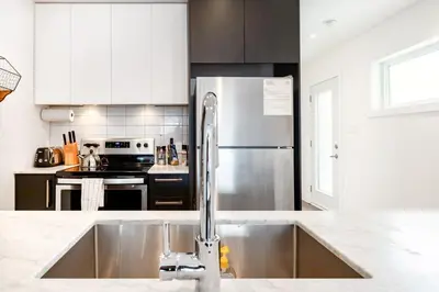 a kitchen with a sink and a stainless steel refrigerator at Hip, Stylish Apartment In Little Italy by Den Stays in Montréal