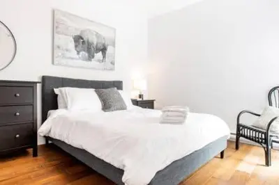 a bedroom with a large bed and a chair at Hip, Stylish Apartment In Little Italy by Den Stays in Montréal