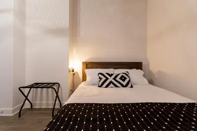 a bed with a black and white pillow on it at Huge 2 Bdr with Balcony in Mile End by Den Stays in Montréal