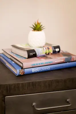 a stack of books sitting on top of a dresser at Huge 2 Bdr with Balcony in Mile End by Den Stays in Montréal