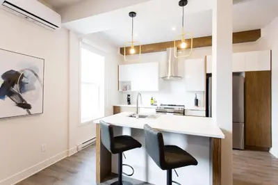 a kitchen with a white counter and two chairs at Huge 2 Bdr with Balcony in Mile End by Den Stays in Montréal