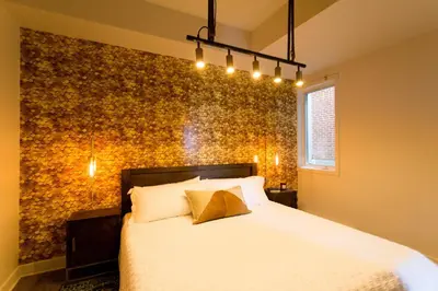 a bedroom with a white bed and a wall with gold at Huge 2 Bdr with Balcony in Mile End by Den Stays in Montréal