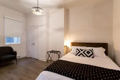 a bedroom with a bed and a chair and a window at Huge 2 Bdr with Balcony in Mile End by Den Stays in Montréal