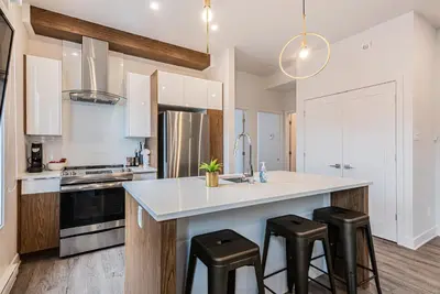 a kitchen with a large white counter and stools at 2 Bedroom Luxury in the Mile End by Den Stays in Montréal