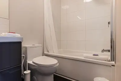 a white bathroom with a toilet and a bath tub at 2 Bedroom Luxury in the Mile End by Den Stays in Montréal