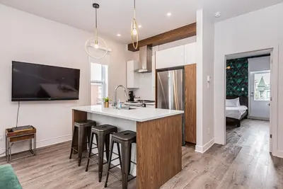 an open kitchen with a sink and bar stools at 2 Bedroom Luxury in the Mile End by Den Stays in Montréal