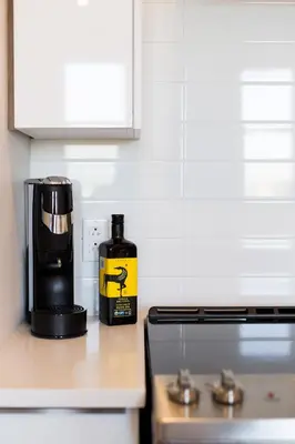 a bottle of alcohol sitting on a counter next to a coffee maker at Perfectly Located Mile End 2 Bdr Unit by Den Stays in Montréal