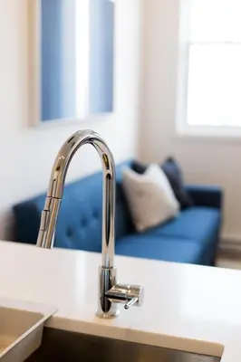 a kitchen sink with a chrome faucet and a couch at Perfectly Located Mile End 2 Bdr Unit by Den Stays in Montréal