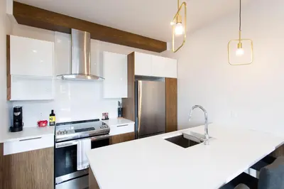 a kitchen with white counters and a white counter top at Light Filled 2 Bdr Unit in Mile End by Den Stays in Montréal