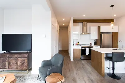 a kitchen and living room with a couch and a chair at Light Filled 2 Bdr Unit in Mile End by Den Stays in Montréal