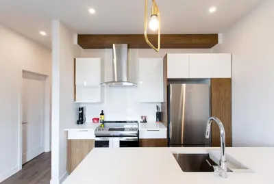 a kitchen with white cabinets and a stainless steel refrigerator at Light Filled 2 Bdr Unit in Mile End by Den Stays in Montréal