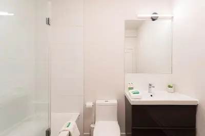 a bathroom with a toilet and a sink and a mirror at Light Filled 2 Bdr Unit in Mile End by Den Stays in Montréal