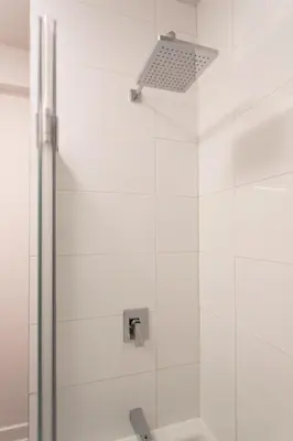 a shower with a white tile wall at Light Filled 2 Bdr Unit in Mile End by Den Stays in Montréal