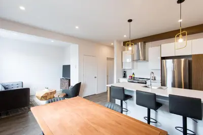 a kitchen and living room with a wooden table at Light Filled 2 Bdr Unit in Mile End by Den Stays in Montréal