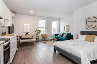 a bedroom with a king sized bed and a kitchen at Brand New and Perfectly Located Flat in Le Plateau by Den Stays in Montréal
