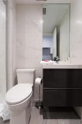 a white bathroom with a toilet and a sink at Studio Palms Steps from JeanTalon Market Full Bath by Den Stays in Montréal