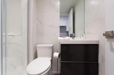 a white bathroom with a toilet and a sink at Studio Palms Steps from JeanTalon Market Full Bath by Den Stays in Montréal