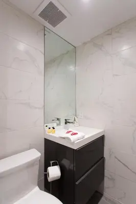 a white bathroom with a sink and a mirror at Studio Palms Steps from JeanTalon Market Full Bath by Den Stays in Montréal