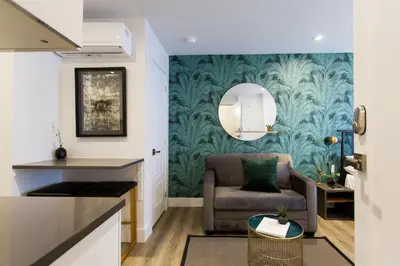 a living room with a chair and a wall mural at Studio Palms Steps from JeanTalon Market Full Bath by Den Stays in Montréal