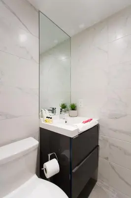 a white bathroom with a sink and a mirror at Romantic Studio in the Heart of Little Italy by Den Stays in Montréal