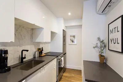 a kitchen with white cabinets and a sink at Romantic Studio in the Heart of Little Italy by Den Stays in Montréal