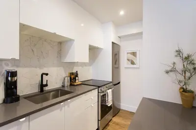 a white kitchen with a sink and a counter top at Romantic Studio in the Heart of Little Italy by Den Stays in Montréal