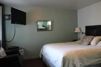 a hotel room with a bed and a mirror at Le Marigot in Vaudreuil-Dorion