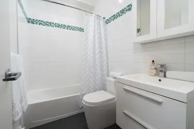 a white bathroom with a toilet and a sink at Hotel-Apart Prince Arthur in Montréal