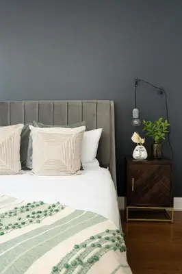 a bed with a gray headboard and a table with a plant at Hotel-Apart Prince Arthur in Montréal