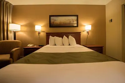 a hotel room with a bed with two chairs and a phone at Quality Inn & Suites PE Trudeau Airport in Dorval
