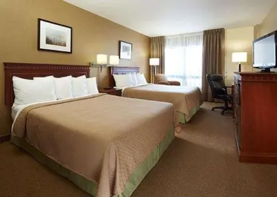a hotel room with two beds and a television at Quality Inn & Suites PE Trudeau Airport in Dorval