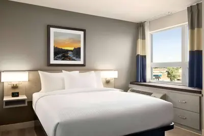 a bedroom with a large white bed and two windows at Microtel Inn & Suites Dorval QC in Dorval