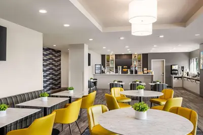 a restaurant with tables and yellow chairs at Microtel Inn & Suites Dorval QC in Dorval