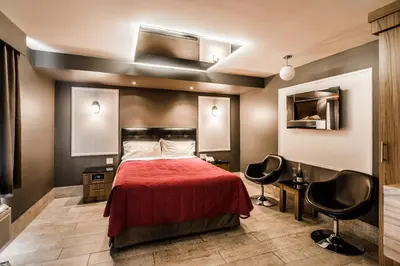 a bedroom with a red bed and two chairs at Olux Hotel-Motel-Suites in Laval