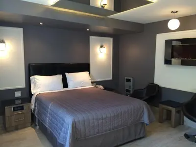 a bedroom with a large bed and two lights at Olux Hotel-Motel-Suites in Laval