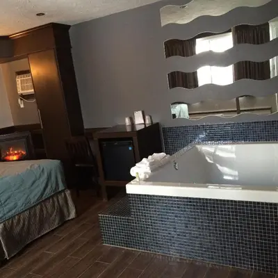 a bathroom with a tub in a room with a bed at Olux Hotel-Motel-Suites in Laval